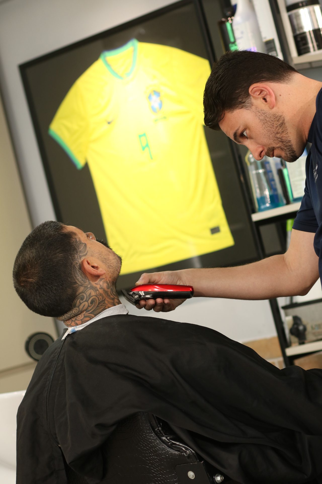 Barbeiro atendendo com a camisa da seleção ao fundo